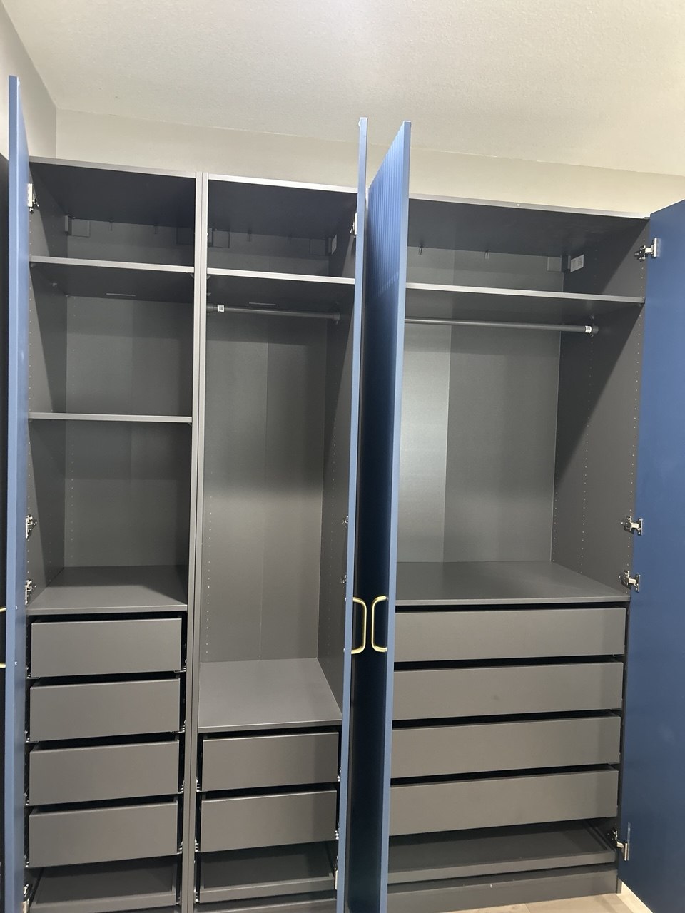 Navy wardrobe system opened to show shelves, drawers, and hanging rails