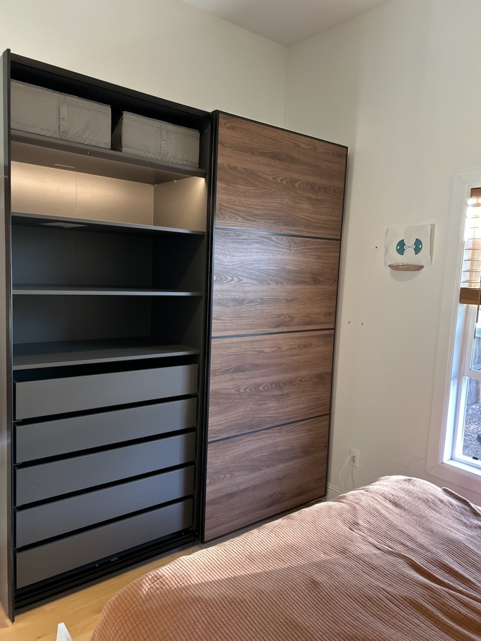 Dark wardrobe with a wood-grain sliding door and an open section of shelves and drawers